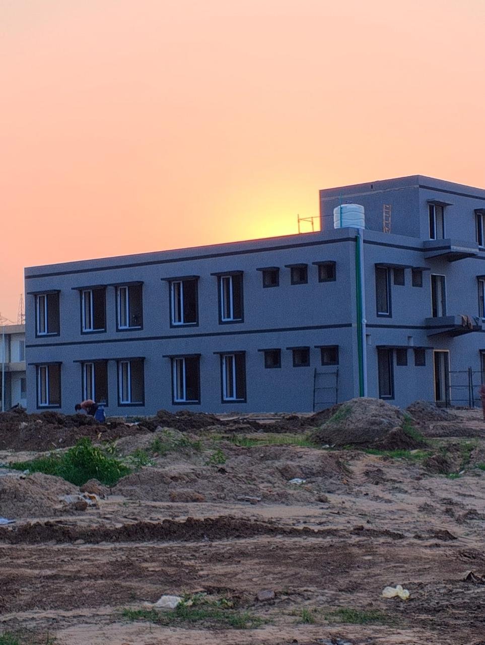 Residential building exterior at sunset, with surrounding works in progress.